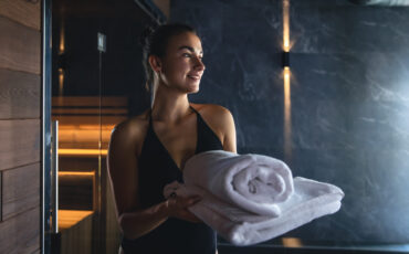 Attractive young woman with towels is relaxing in the sauna.